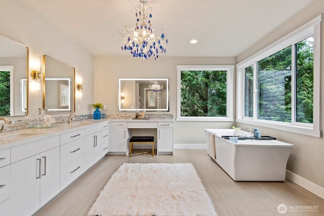 full bath with a sink, a notable chandelier, a soaking tub, and double vanity