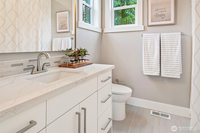 bathroom with visible vents, toilet, decorative backsplash, baseboards, and vanity