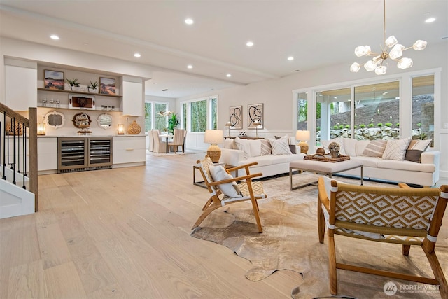 living room with stairway, recessed lighting, wine cooler, light wood-style floors, and a notable chandelier