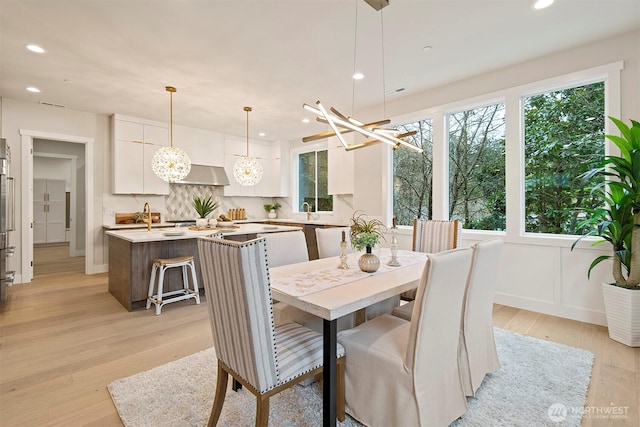 dining space featuring recessed lighting, a notable chandelier, and light wood-style flooring