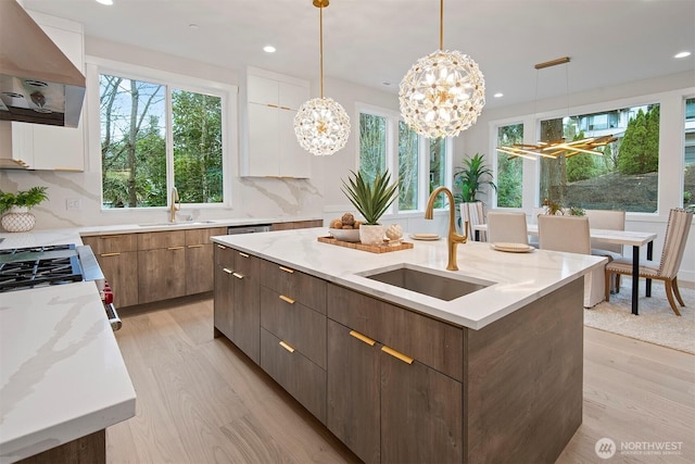 kitchen with extractor fan, modern cabinets, a center island with sink, and a sink