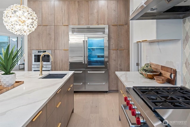 kitchen featuring stainless steel appliances, light stone countertops, modern cabinets, and wall chimney exhaust hood