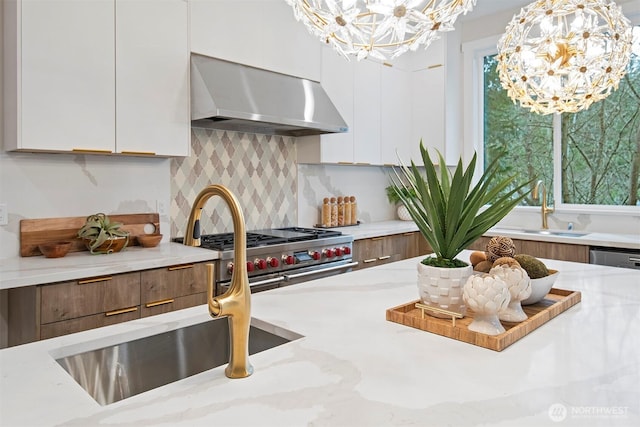 kitchen with a chandelier, white cabinetry, modern cabinets, and wall chimney range hood