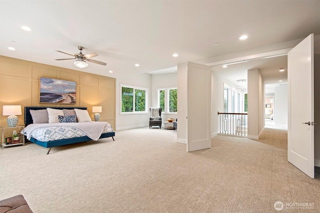 bedroom featuring a ceiling fan, a decorative wall, recessed lighting, and light carpet