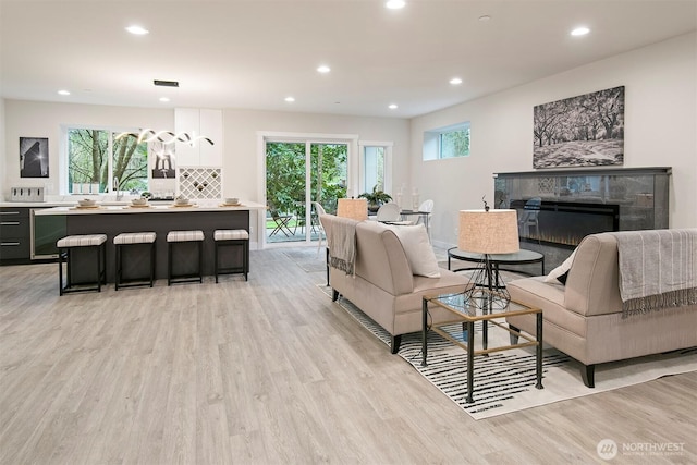 living room with visible vents, a tiled fireplace, wine cooler, recessed lighting, and light wood-style flooring