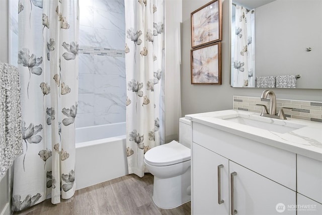 full bathroom featuring tasteful backsplash, toilet, shower / bath combo, wood finished floors, and vanity