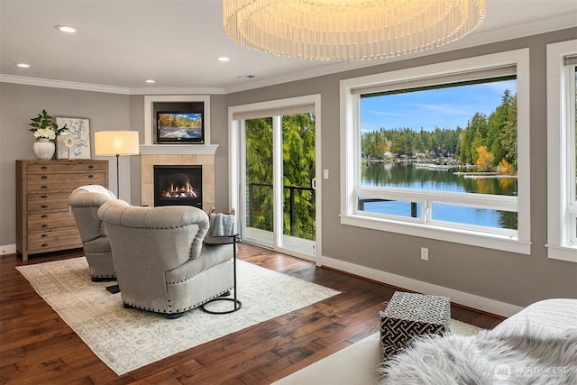 living room featuring dark wood finished floors, a water view, ornamental molding, and a tiled fireplace