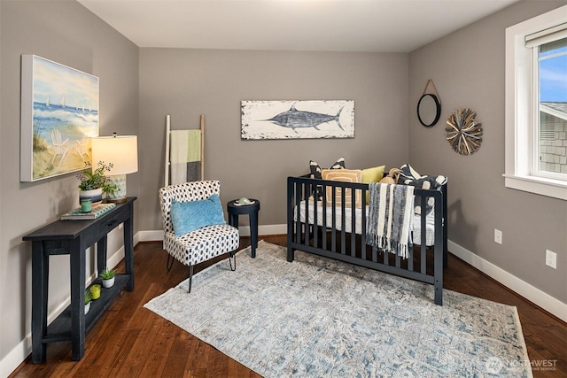 bedroom with a nursery area, wood finished floors, and baseboards