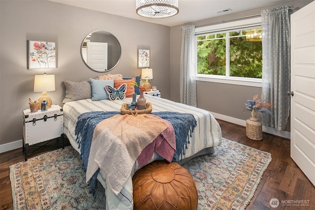 bedroom featuring visible vents, baseboards, and wood finished floors