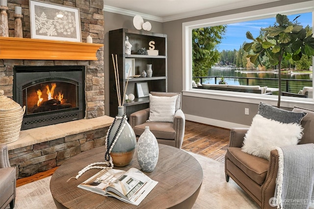 sitting room with baseboards, wood finished floors, a stone fireplace, and ornamental molding