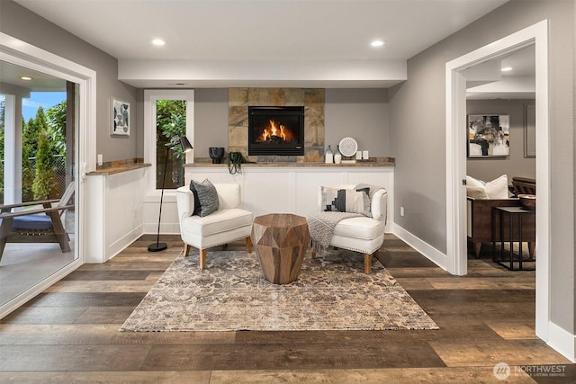 sitting room with recessed lighting, baseboards, a lit fireplace, and dark wood-style flooring