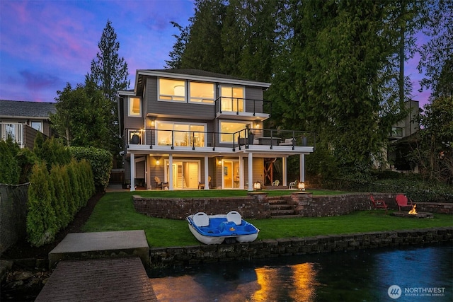 rear view of house with a yard, a patio, a balcony, and a water view