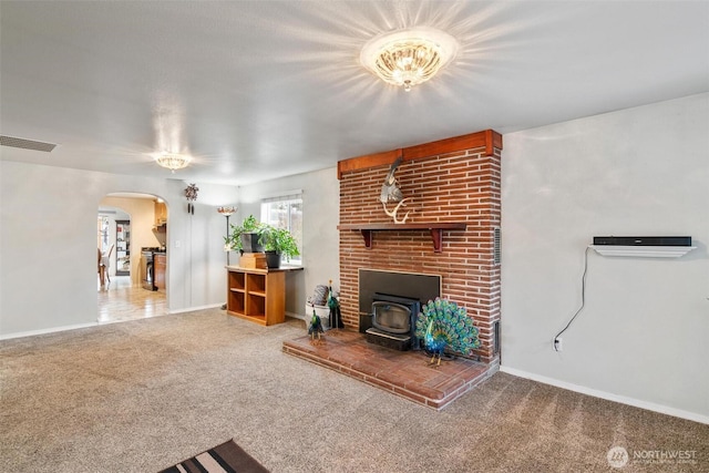 carpeted living room featuring arched walkways, visible vents, a wood stove, and baseboards