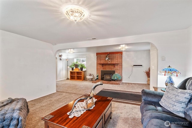 carpeted living area with visible vents, arched walkways, and a wood stove