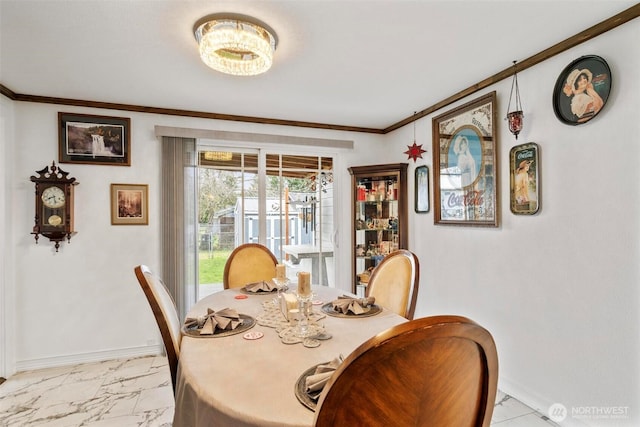 dining room featuring a chandelier, marble finish floor, baseboards, and ornamental molding