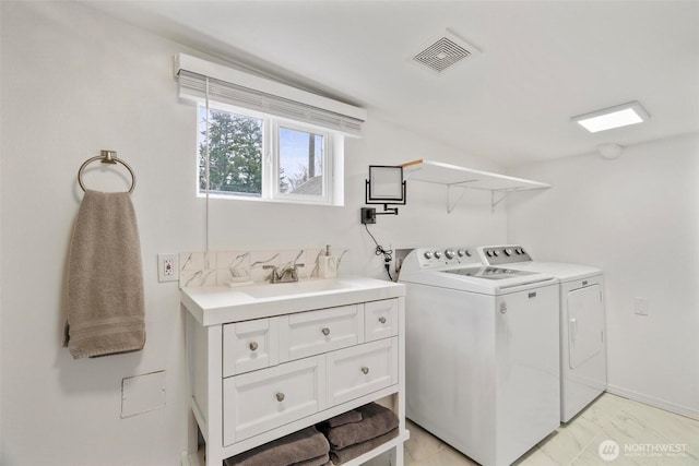 clothes washing area featuring a sink, visible vents, laundry area, and washer and clothes dryer