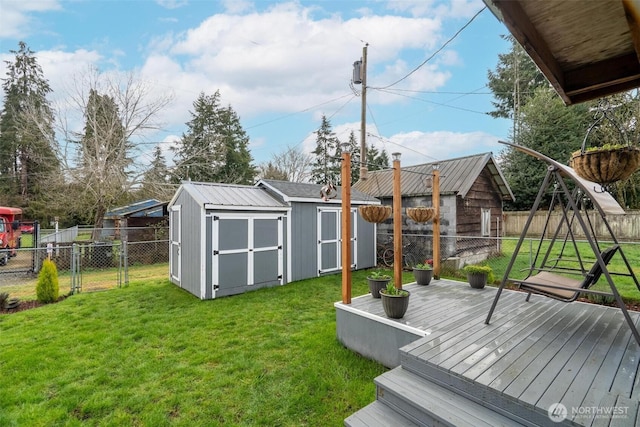 view of yard featuring fence, a wooden deck, a storage shed, an outdoor structure, and a gate