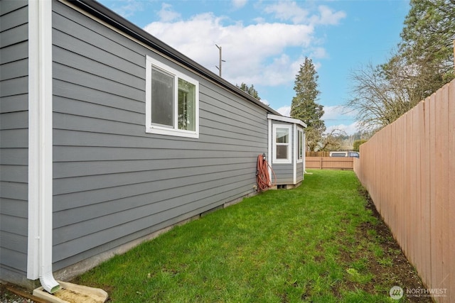 view of side of property featuring a lawn and a fenced backyard