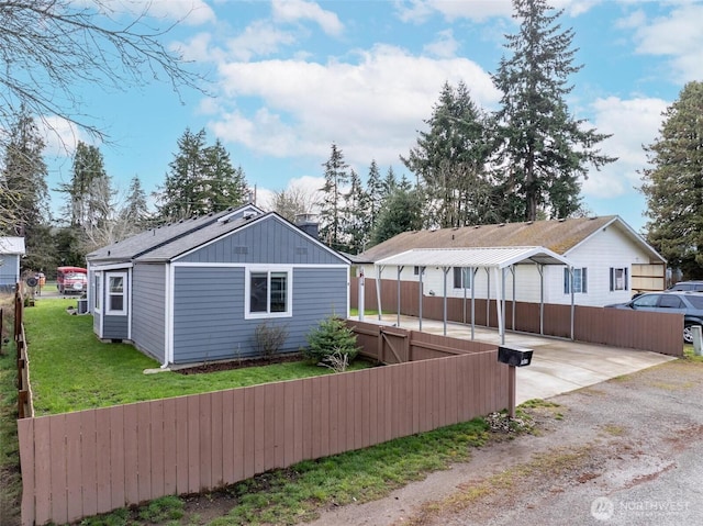 rear view of property with driveway, a yard, and fence