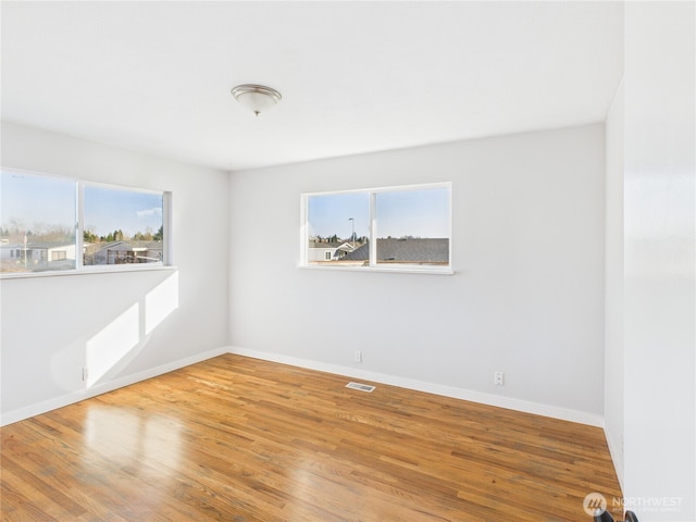 empty room featuring visible vents, baseboards, and wood finished floors