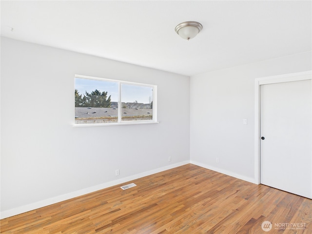 empty room with light wood-type flooring, visible vents, and baseboards