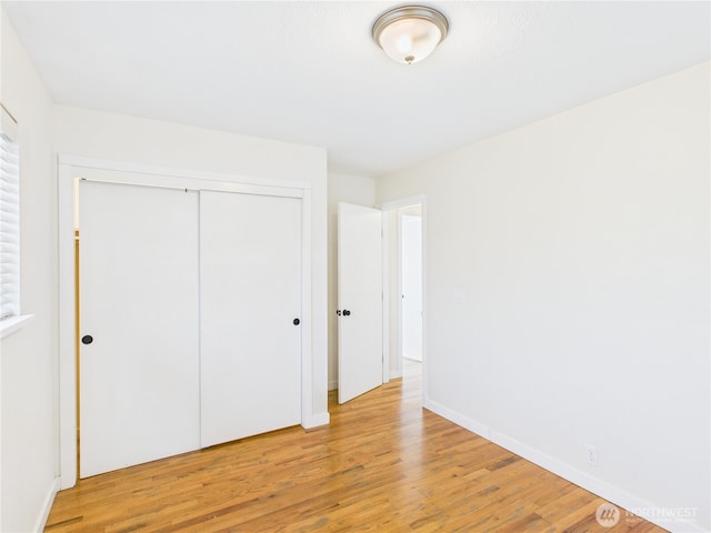 unfurnished bedroom with a closet, light wood-type flooring, and baseboards