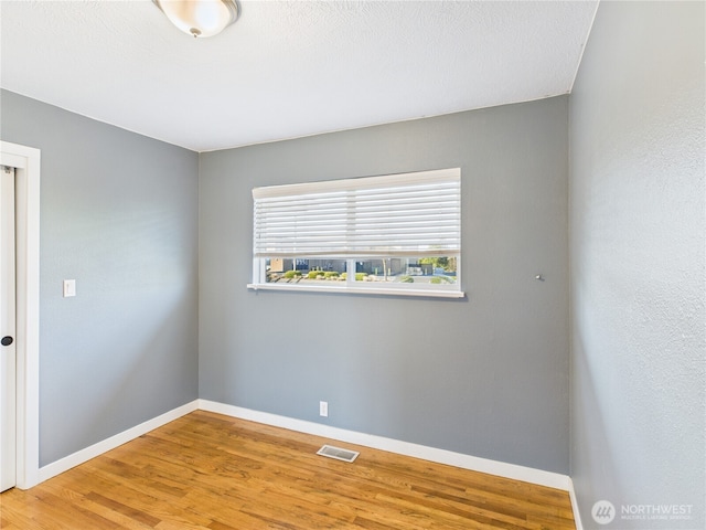 spare room with visible vents, baseboards, and wood finished floors