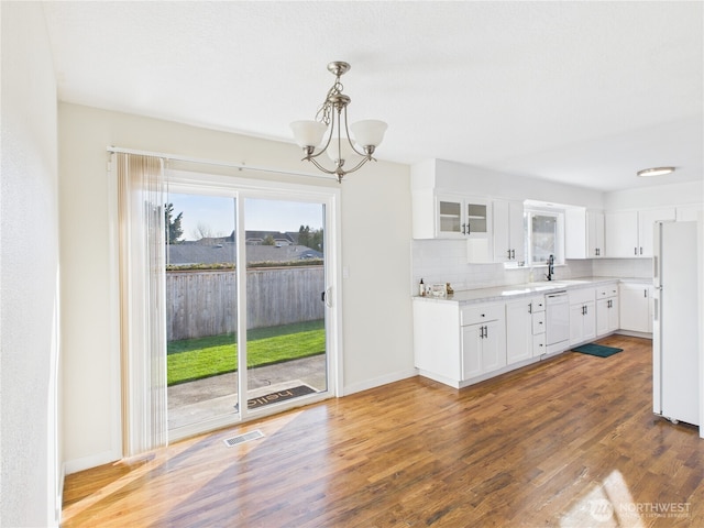 kitchen with visible vents, tasteful backsplash, wood finished floors, white appliances, and white cabinets