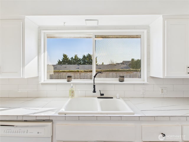 kitchen featuring a sink, white cabinets, white dishwasher, and light countertops