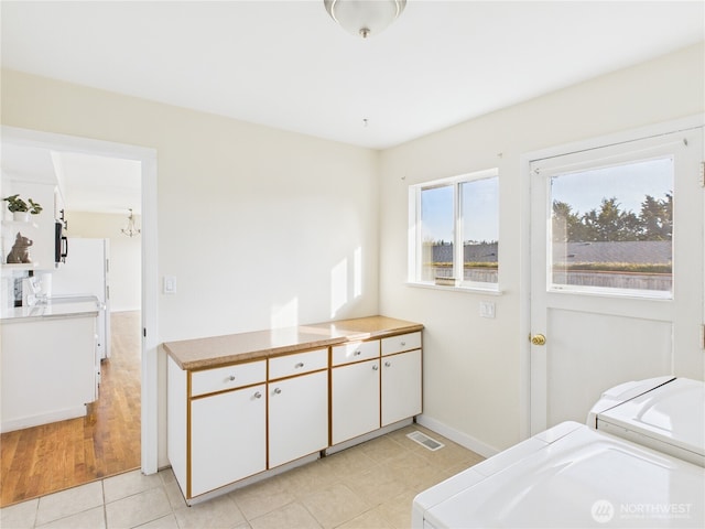 laundry room with visible vents, baseboards, a chandelier, light tile patterned floors, and independent washer and dryer