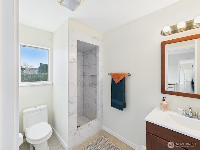 bathroom featuring baseboards, toilet, vanity, and a tile shower