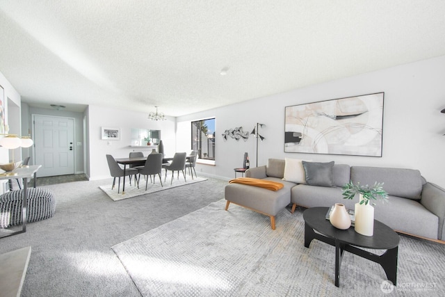 carpeted living room featuring baseboards, a textured ceiling, and a chandelier