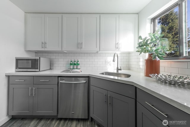 kitchen featuring a sink, stainless steel appliances, backsplash, and gray cabinets