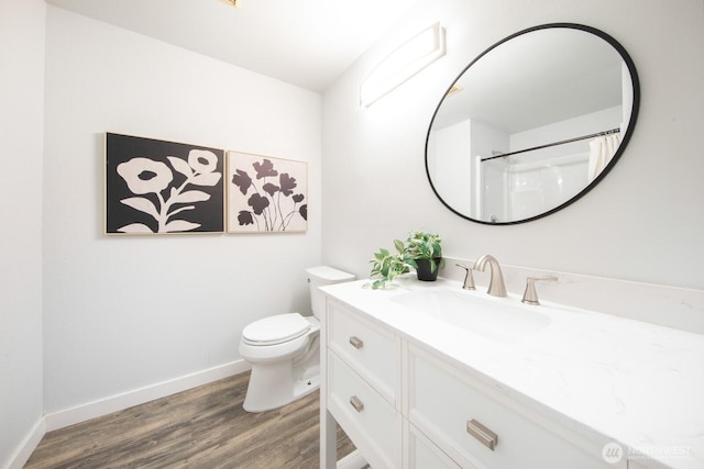 full bath featuring toilet, vanity, baseboards, and wood finished floors