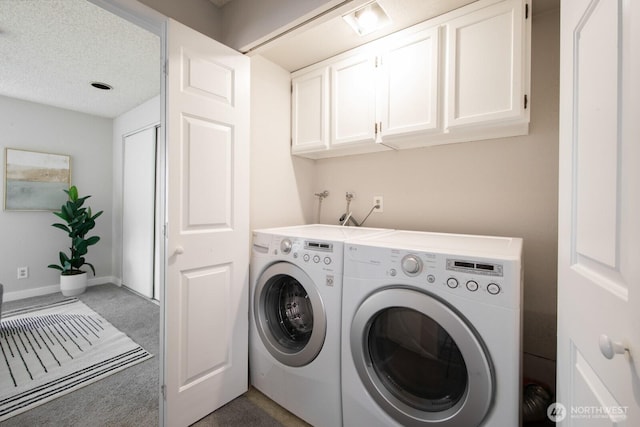 laundry room with baseboards, washing machine and clothes dryer, cabinet space, a textured ceiling, and dark colored carpet