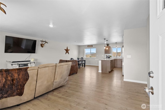 living area featuring baseboards and light wood-style flooring