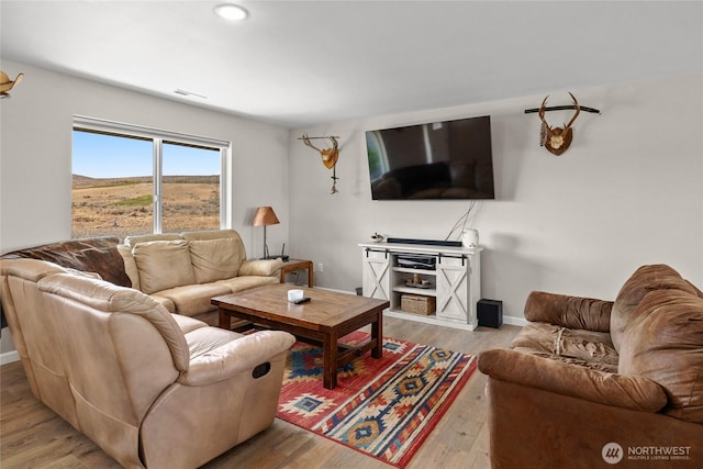 living area with visible vents, baseboards, and wood finished floors