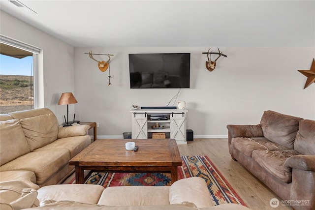 living area featuring visible vents, wood finished floors, and baseboards