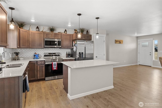 kitchen featuring a sink, decorative backsplash, light wood finished floors, and stainless steel appliances