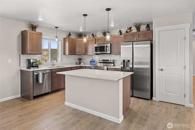 kitchen with backsplash, light wood finished floors, appliances with stainless steel finishes, and a sink