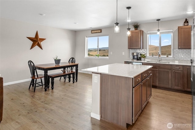 kitchen featuring light wood finished floors, backsplash, a center island, and a sink