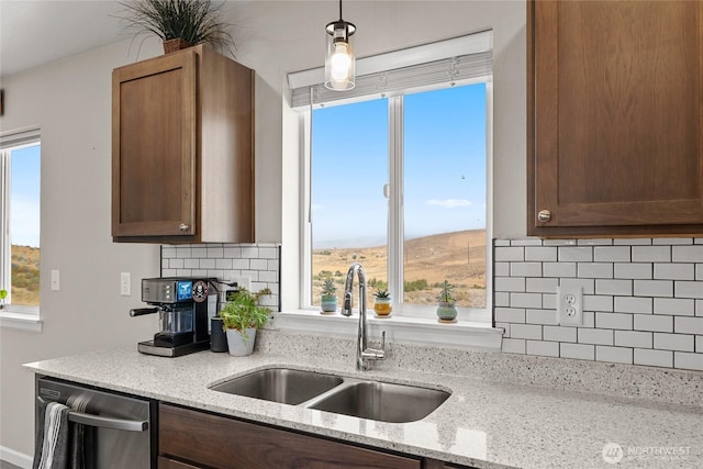 kitchen featuring a sink, decorative light fixtures, light stone counters, backsplash, and dishwasher