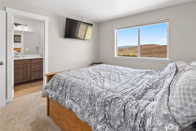 bedroom featuring light colored carpet and ensuite bathroom