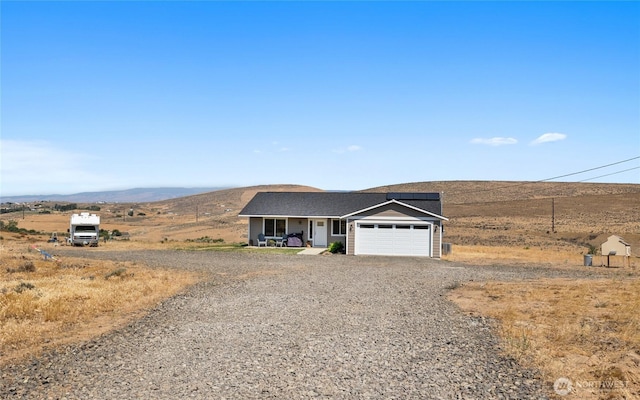 view of front facade featuring a mountain view, an attached garage, covered porch, and driveway