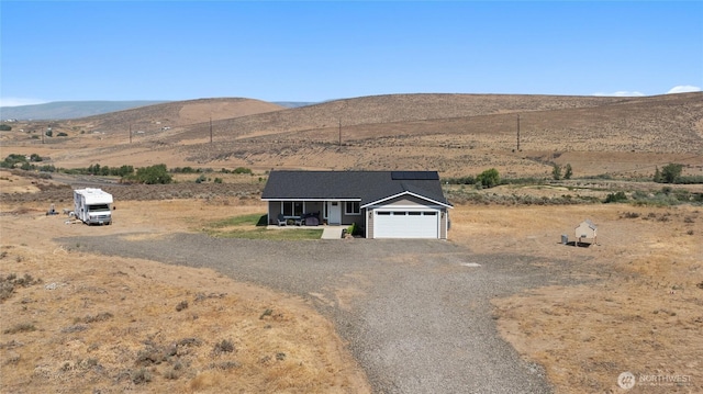 view of front of property with solar panels, a mountain view, driveway, and a garage