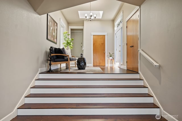 stairway featuring wood finished floors, baseboards, and a chandelier