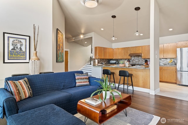 living room with stairway, recessed lighting, wood-type flooring, and high vaulted ceiling