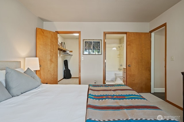 carpeted bedroom with ensuite bath, a spacious closet, baseboards, and a closet