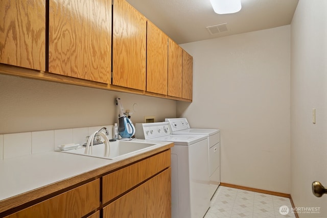clothes washing area with visible vents, a sink, washing machine and dryer, cabinet space, and light floors