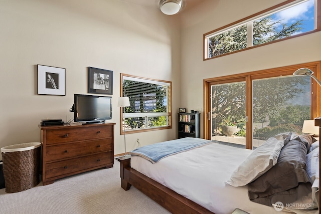 bedroom featuring light colored carpet and a towering ceiling